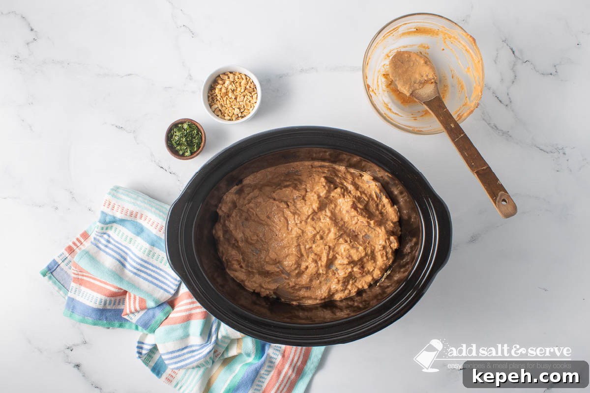 Slow Cooker Thai Peanut Chicken Recipe 6 A slow cooker with chicken covered in a peanut sauce before cooking.