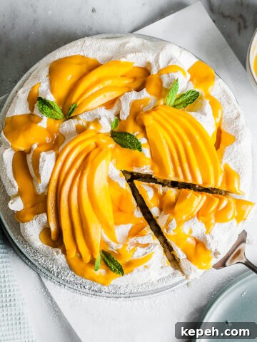 A coconut cake with baked meringue decorated with mango slices.