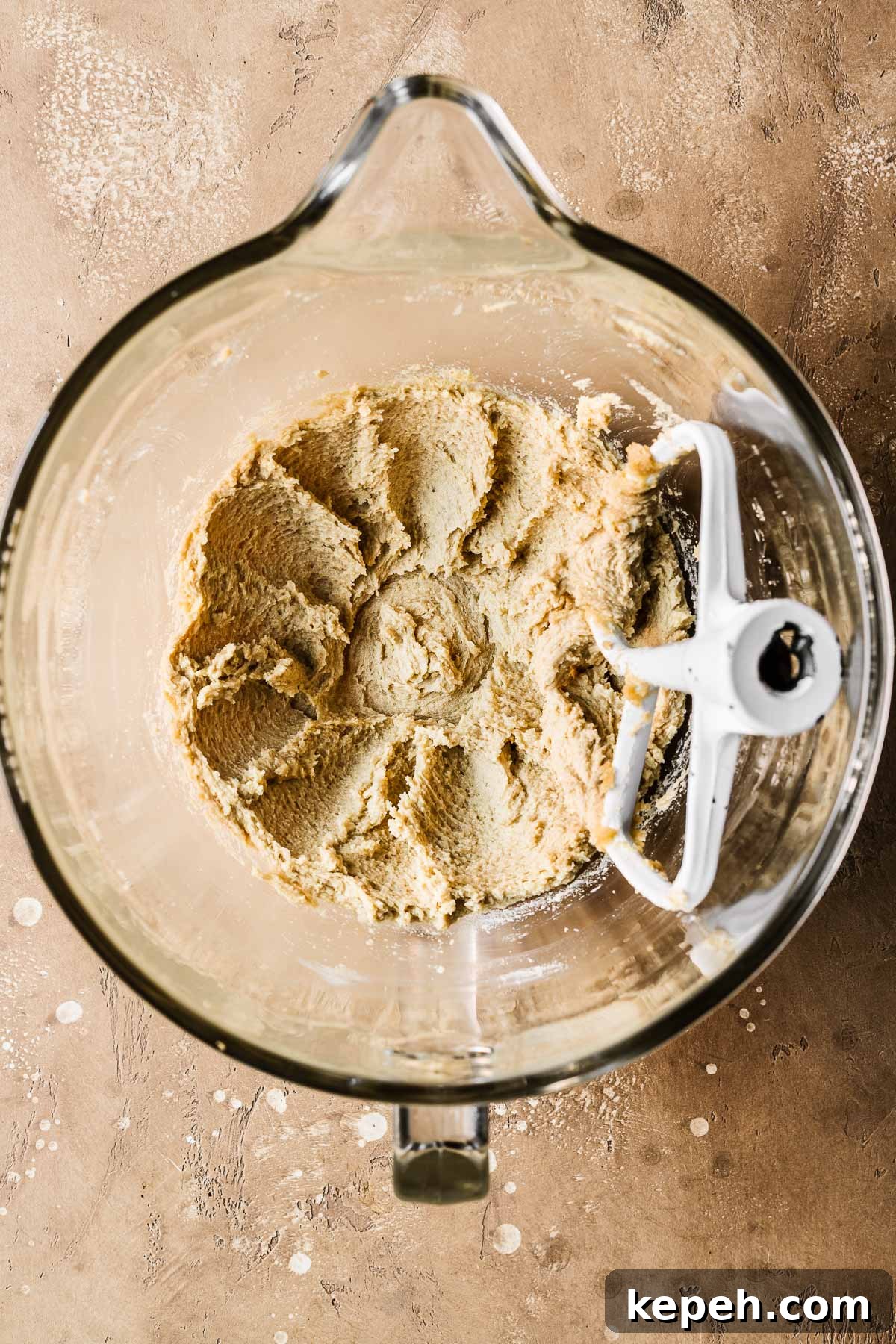 Butter, sugar and eggs mixed together in a clear glass mixing bowl.