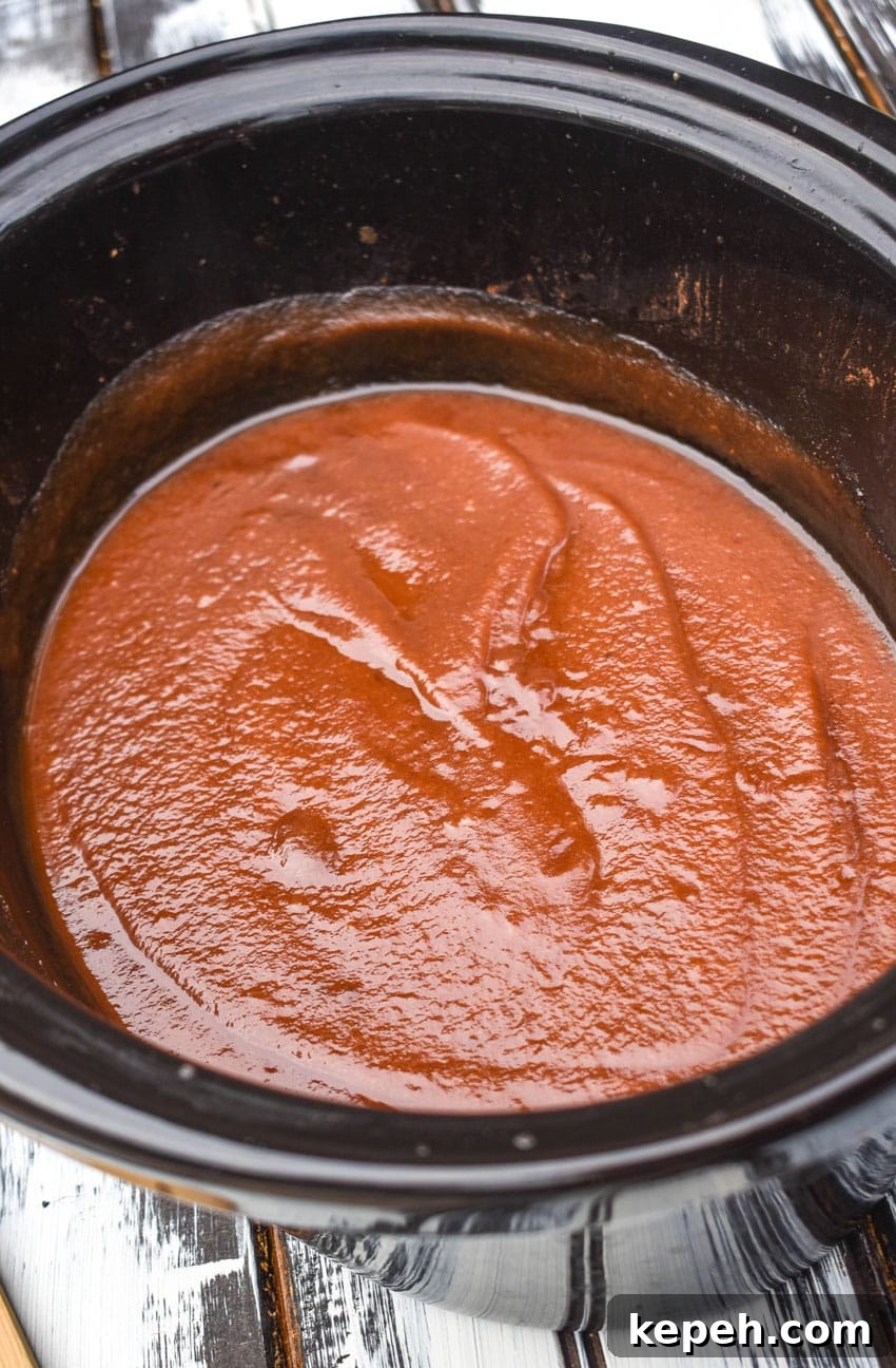 homemade apple butter in the black crock of a slow cooker